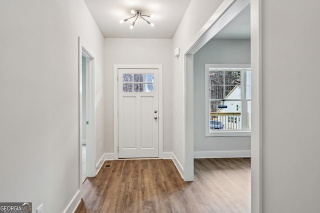 foyer featuring a notable chandelier, baseboards, and wood finished floors