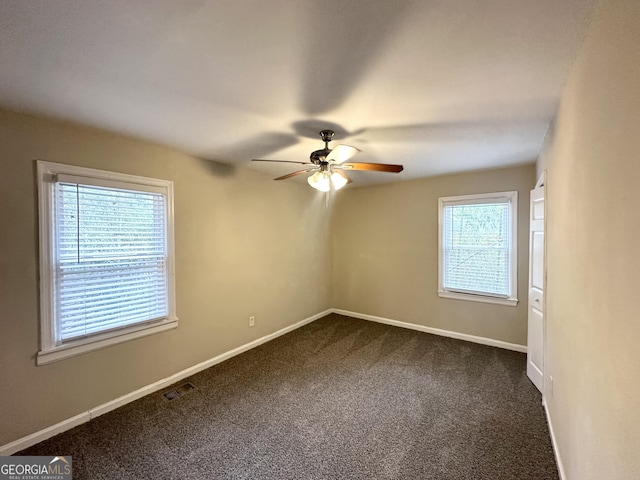 empty room featuring visible vents, a ceiling fan, baseboards, and dark colored carpet