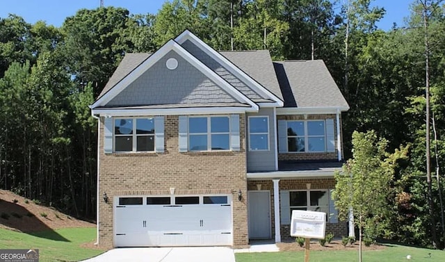 craftsman-style home with brick siding, a front yard, an attached garage, and driveway