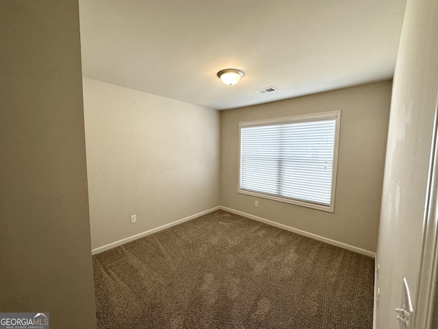 empty room featuring visible vents, baseboards, and dark colored carpet