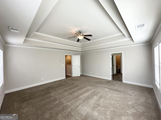 empty room with a tray ceiling, visible vents, and carpet flooring