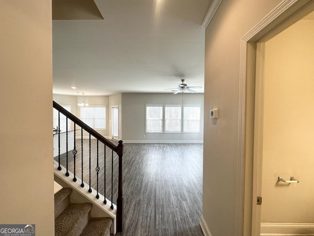 stairway with ceiling fan with notable chandelier, wood finished floors, and baseboards