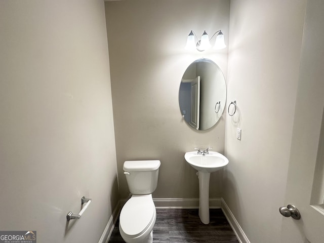 bathroom with a sink, baseboards, toilet, and wood finished floors