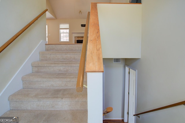 stairway with visible vents and a fireplace