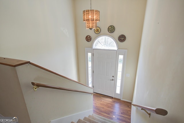 entryway with an inviting chandelier, stairway, and wood finished floors