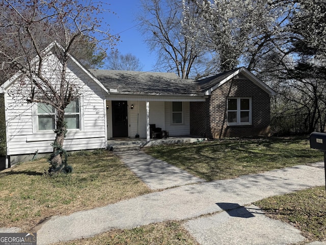 ranch-style home featuring brick siding, a porch, and a front yard