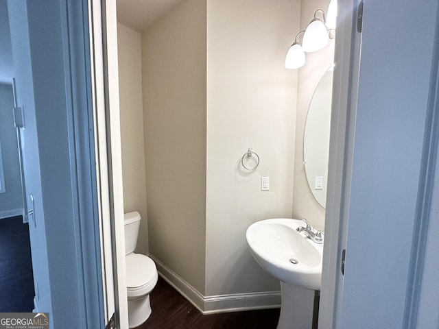 bathroom with a sink, baseboards, toilet, and wood finished floors