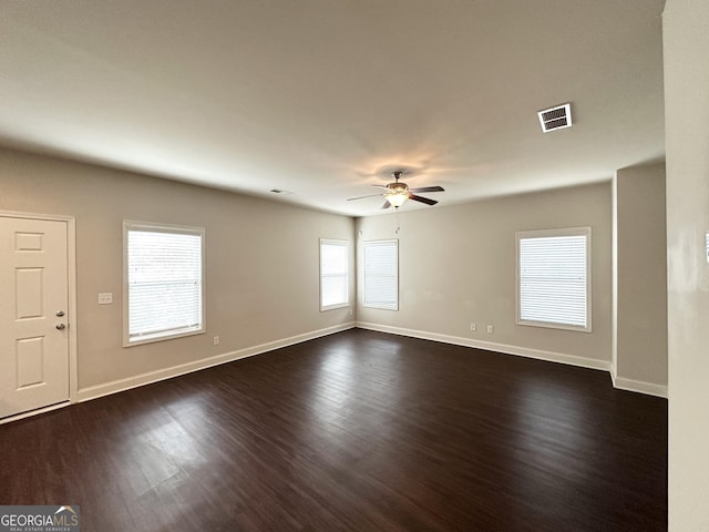 unfurnished room featuring visible vents, baseboards, dark wood finished floors, and a ceiling fan