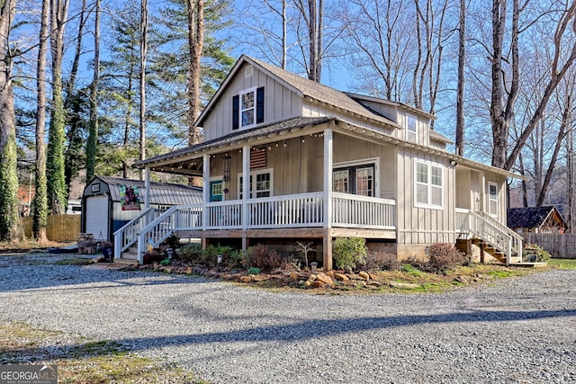 view of front of property featuring board and batten siding, covered porch, an outdoor structure, and driveway