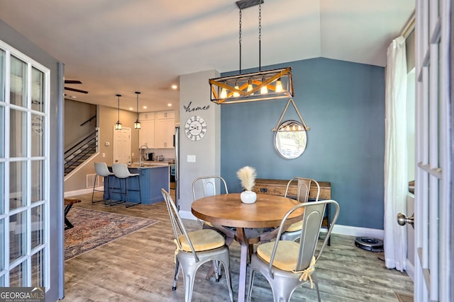 dining area with lofted ceiling, wood finished floors, recessed lighting, baseboards, and stairs