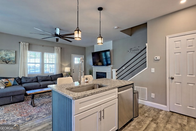 kitchen featuring visible vents, stainless steel dishwasher, open floor plan, white cabinets, and a fireplace