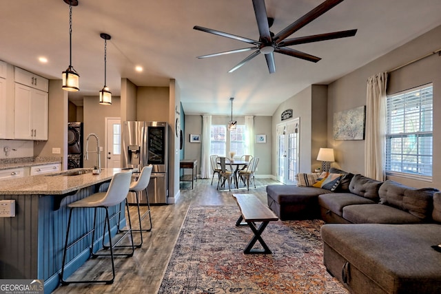 living area with baseboards, washer / clothes dryer, wood finished floors, and a ceiling fan