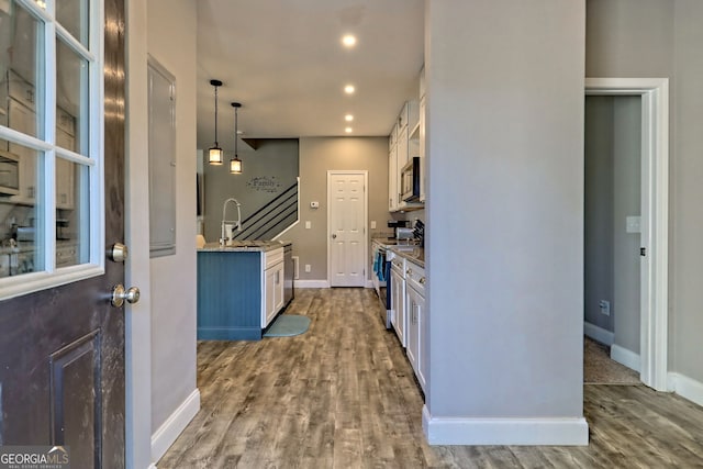 kitchen featuring baseboards, recessed lighting, appliances with stainless steel finishes, wood finished floors, and white cabinets