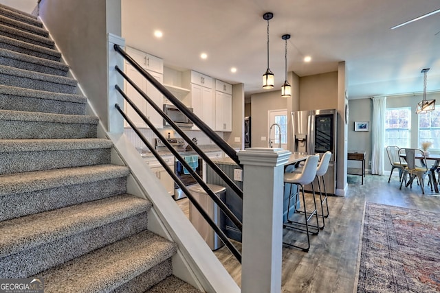 stairs featuring recessed lighting, wood finished floors, baseboards, and a wealth of natural light