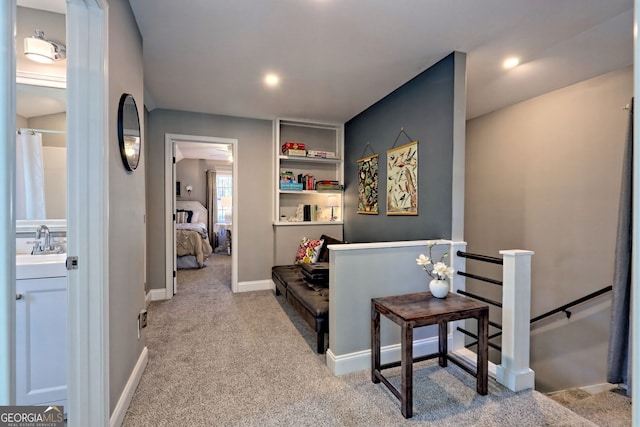 hallway with an upstairs landing, a sink, baseboards, and carpet floors