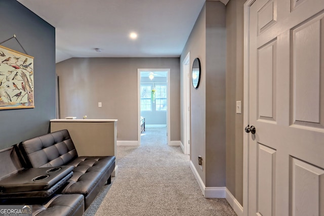 corridor with light colored carpet, lofted ceiling, and baseboards