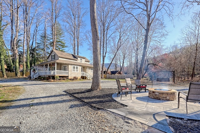 view of yard featuring a patio area, covered porch, an outdoor fire pit, and fence