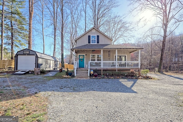 view of front facade featuring an outbuilding, driveway, roof with shingles, a porch, and a storage unit