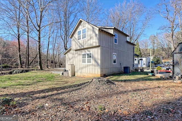 view of property exterior with crawl space, central air condition unit, board and batten siding, and a yard