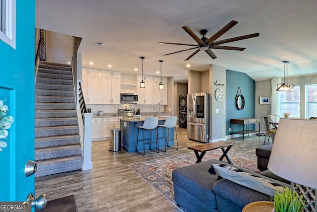 living area featuring stairway, a ceiling fan, lofted ceiling, recessed lighting, and light wood-type flooring