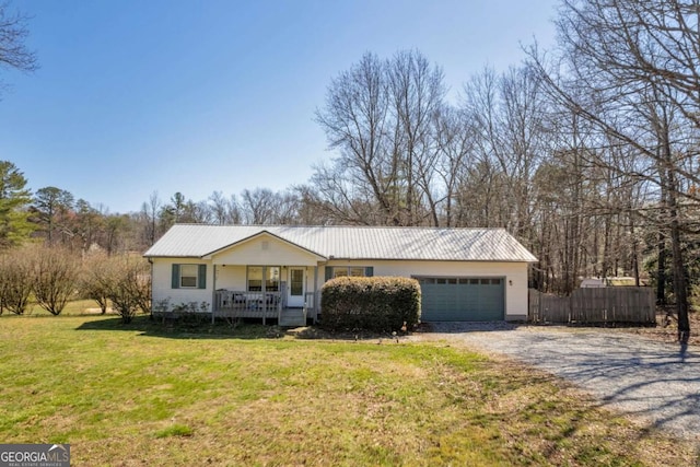 ranch-style home with a front lawn, a porch, gravel driveway, metal roof, and a garage