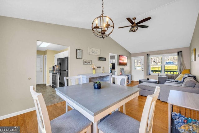 dining area with baseboards, lofted ceiling, a notable chandelier, and wood finished floors