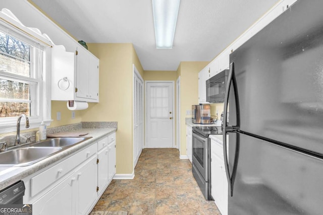 kitchen with black appliances, white cabinets, light countertops, and a sink