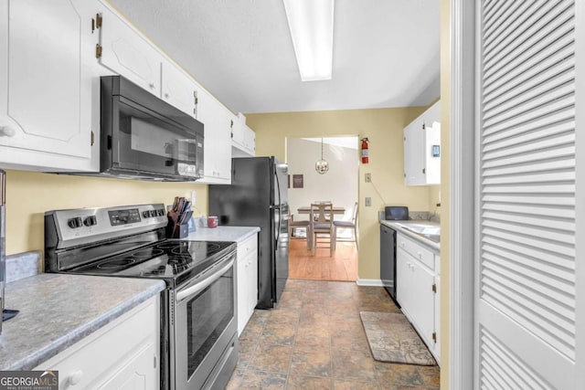 kitchen featuring white cabinetry, black appliances, light countertops, and stone finish flooring