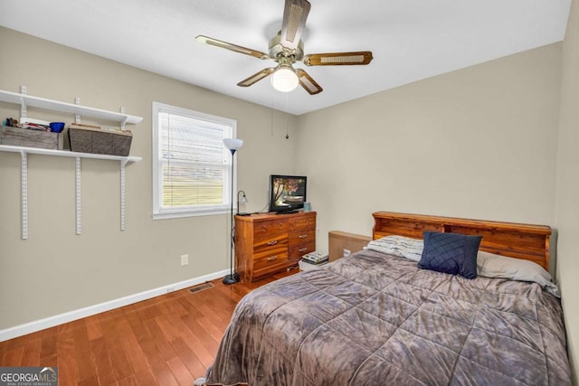 bedroom with visible vents, ceiling fan, baseboards, and wood finished floors