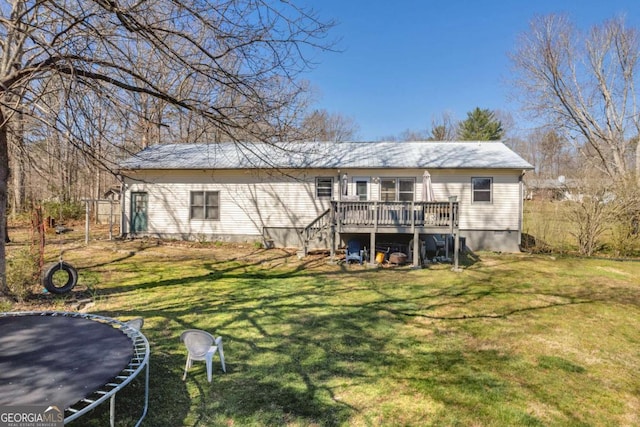 back of property featuring a deck, stairway, a trampoline, and a lawn