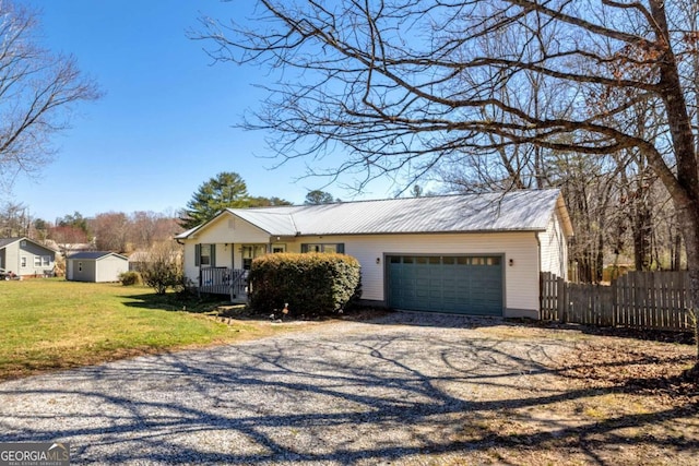 view of front facade with a garage, fence, gravel driveway, a front yard, and metal roof