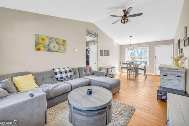 living area featuring light wood finished floors, ceiling fan, baseboards, and lofted ceiling