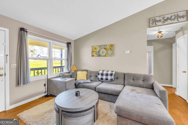 living room with baseboards, lofted ceiling, and wood finished floors