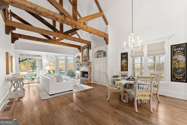 dining room with a notable chandelier, a fireplace, high vaulted ceiling, and wood finished floors