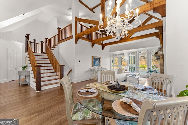 dining room with stairway, wood finished floors, baseboards, high vaulted ceiling, and a chandelier