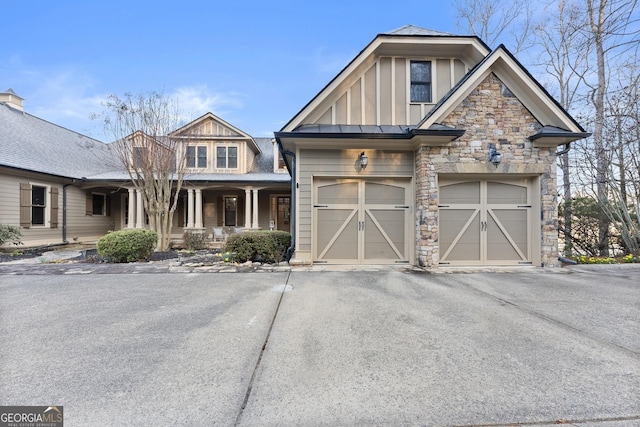 craftsman house with stone siding, a garage, board and batten siding, and driveway