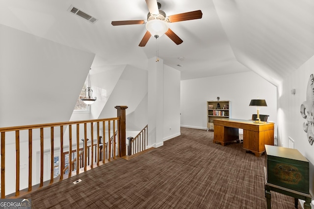 home office with visible vents, ceiling fan, dark carpet, and vaulted ceiling