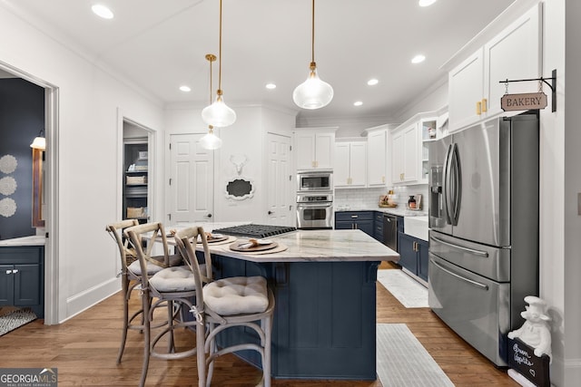 kitchen featuring blue cabinetry, backsplash, a center island, white cabinetry, and appliances with stainless steel finishes