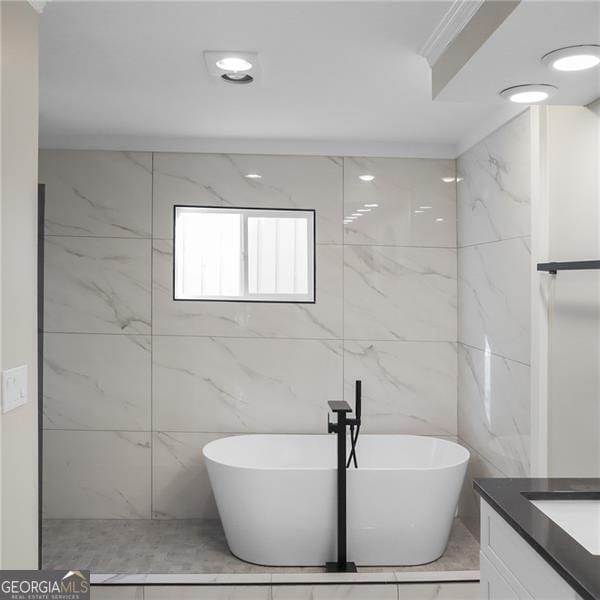 full bathroom featuring a freestanding bath, vanity, and ornamental molding