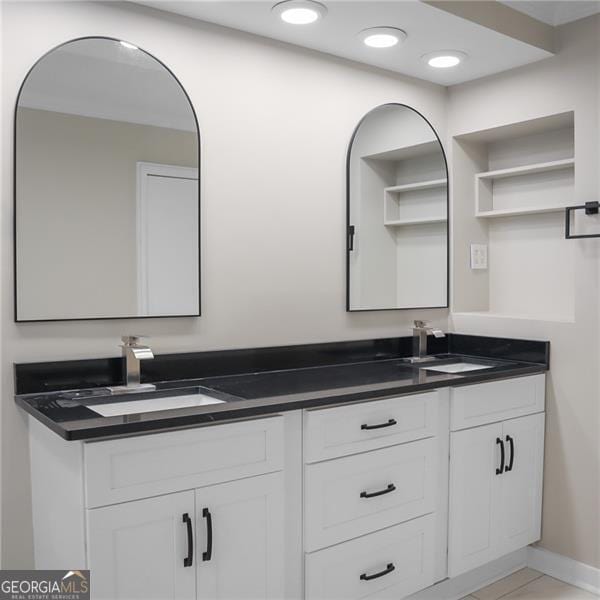 bathroom with a sink, baseboards, recessed lighting, and double vanity