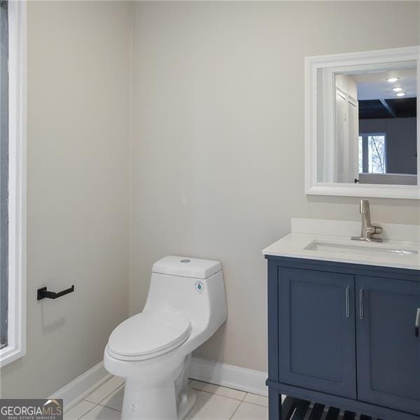 bathroom with tile patterned flooring, toilet, vanity, and baseboards