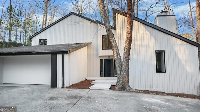 view of front facade featuring an attached garage, driveway, and a chimney