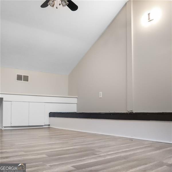 additional living space featuring vaulted ceiling, visible vents, light wood-type flooring, and ceiling fan