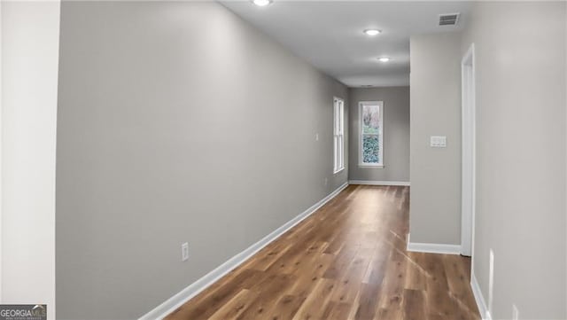 hall with visible vents, baseboards, and wood finished floors