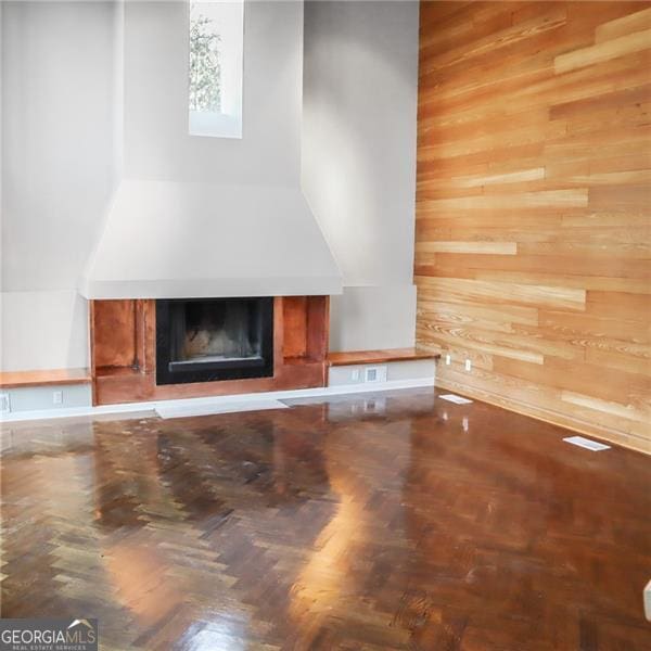 unfurnished living room featuring wooden walls and a fireplace