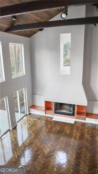 unfurnished living room featuring vaulted ceiling with beams and a premium fireplace