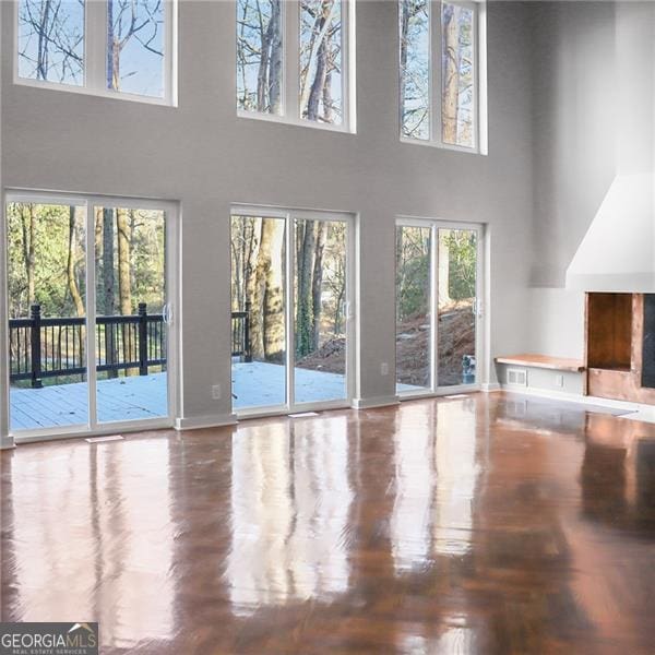 unfurnished living room featuring visible vents, plenty of natural light, and a high ceiling