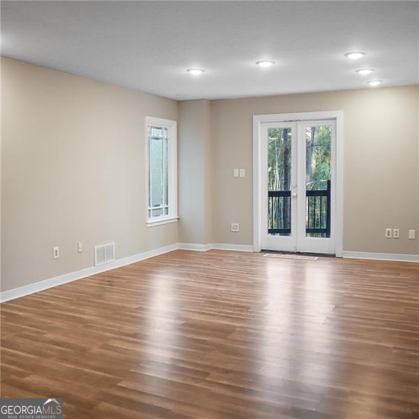 unfurnished room with visible vents, wood finished floors, recessed lighting, french doors, and baseboards