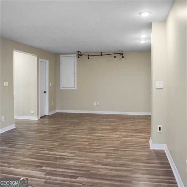 spare room featuring baseboards and wood finished floors