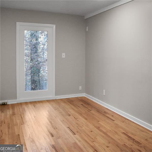 empty room with baseboards, plenty of natural light, and wood finished floors